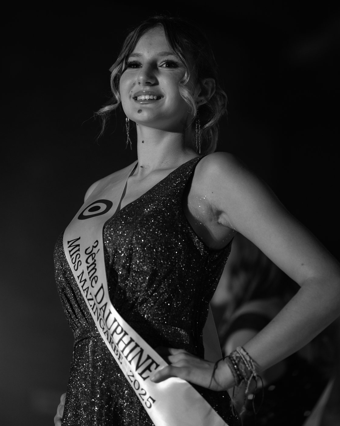 Léna Fiba en noir et blanc, robe pailletée, portant l'écharpe de 3e dauphine de Miss Mazingarbe 2025, main sur la hanche