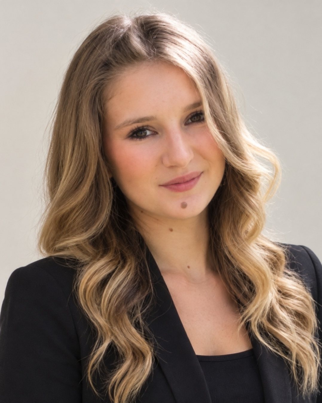 Portrait de Léna Fiba, longs cheveux blonds ondulés, veste noire, sur fond clair